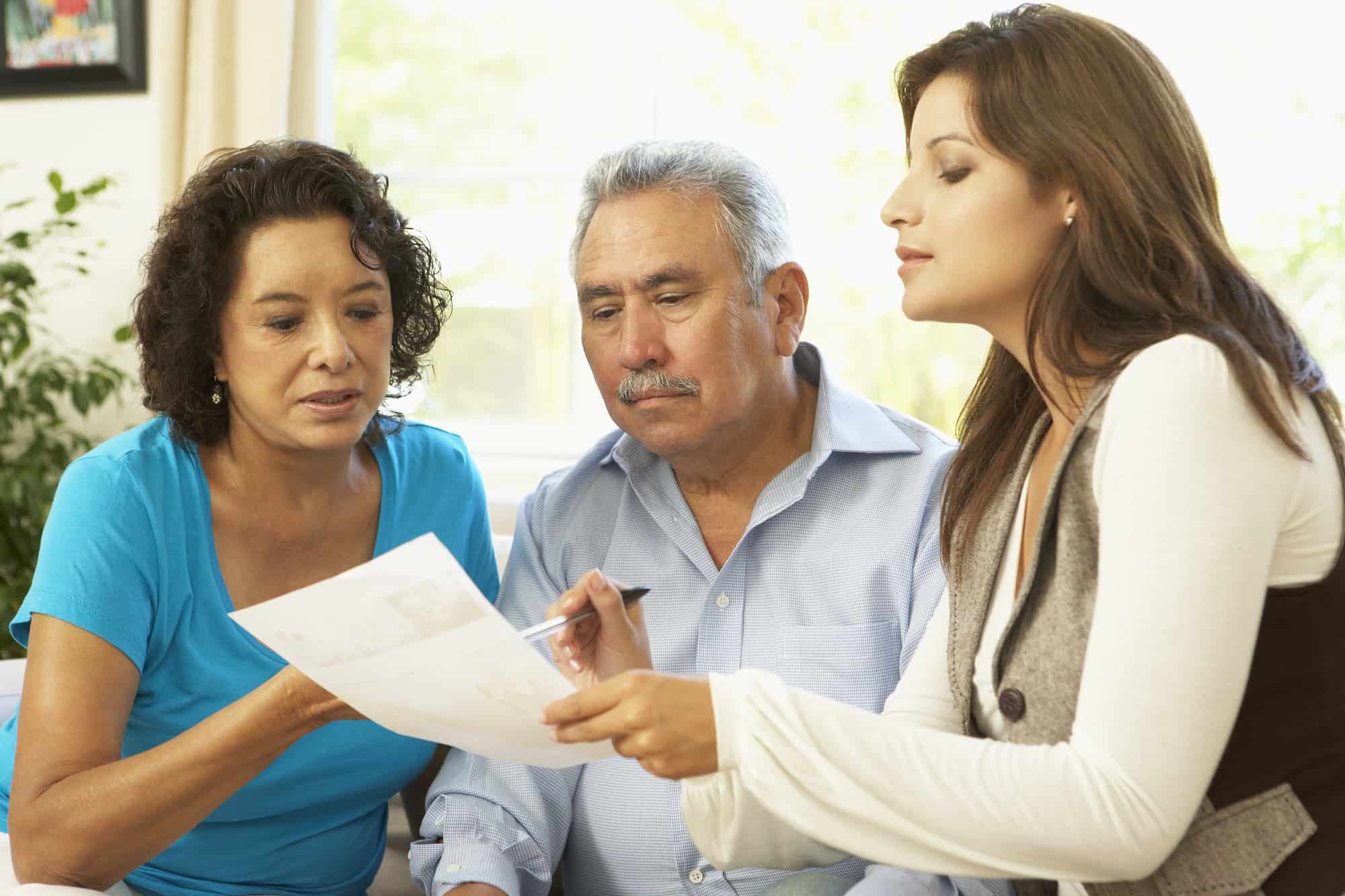 Asesora financiera explicando a una familia latina las estrategias para manejar la deuda de tarjetas de crédito empresariales.
